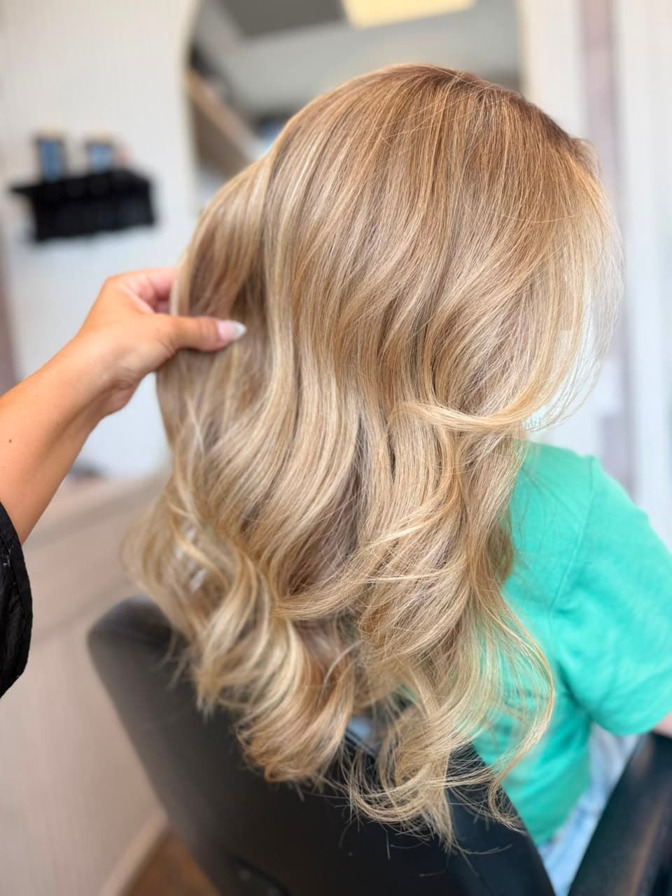 Glossy beige blonde waves being styled in the atelier chair