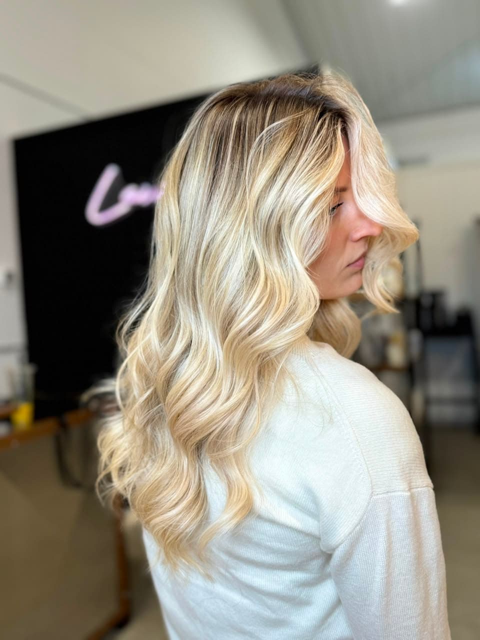 Long bright blonde waves with a soft root, seen from the side