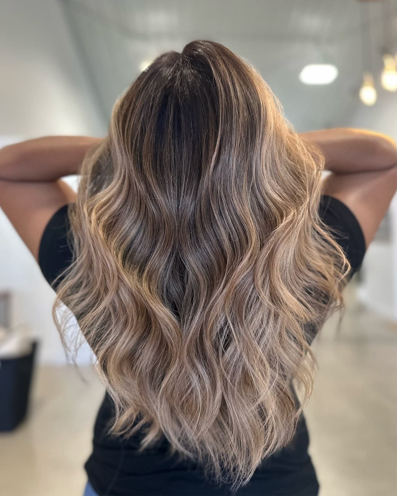 Back view of long waves melting from deep brown roots into beige blonde ends