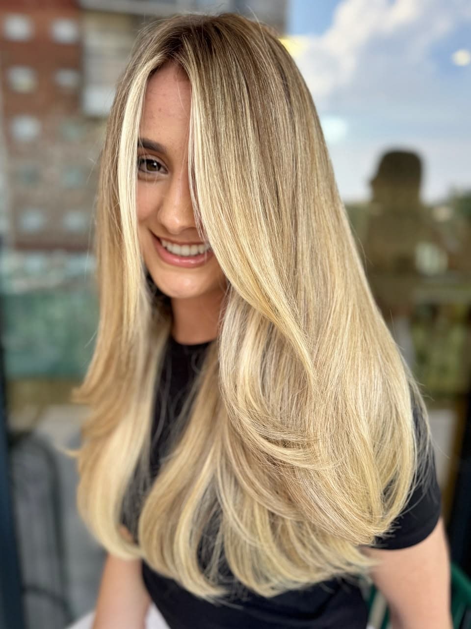 Smiling client with long, glossy golden blonde layers